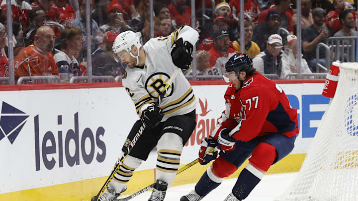 Apr 15, 2024; Washington, District of Columbia, USA; Boston Bruins defenseman Kevin Shattenkirk (12) skates with the puck as Washington Capitals right wing T.J. Oshie (77) defends in the third period at Capital One Arena. Mandatory Credit: Geoff Burke-Imagn Images