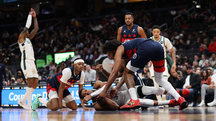 Dec 1, 2025; Washington, District of Columbia, USA; Milwaukee Bucks forward Giannis Antetokounmpo (34) dives to the floor while battling for a loose ball with Washington Wizards forward Marvin Bagley III (35) and Wizards guard Bilal Coulibaly (0) in the first half at Capital One Arena. Mandatory Credit: Geoff Burke-Imagn Images