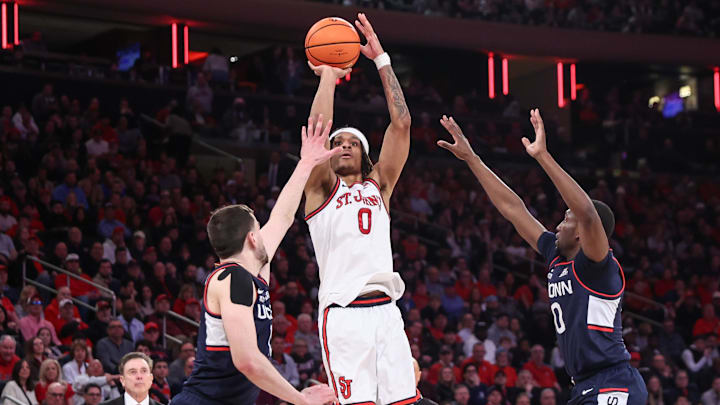 Aaron Scott takes a three-point shot past UConn forward Alex Karaban, left, and guard Ahmad Nowell.