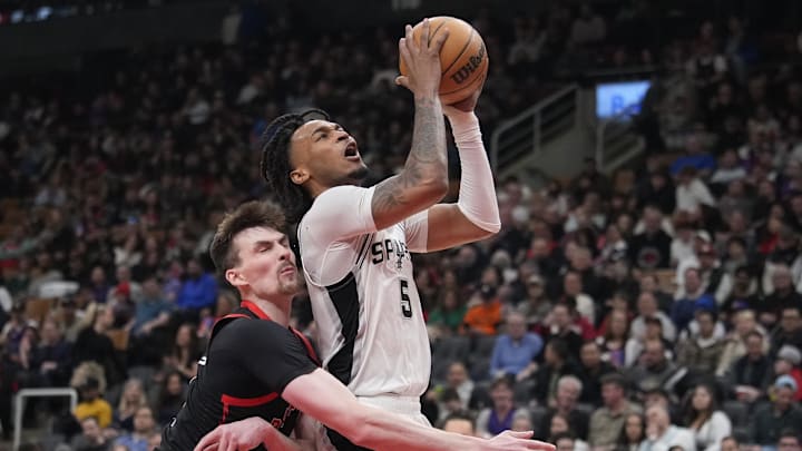 Mar 23, 2025; Toronto, Ontario, CAN; San Antonio Spurs guard Stephon Castle (5) goes up to make a basket against Toronto Raptors center Colin Castleton (11) during the second half at Scotiabank Arena. Mandatory Credit: John E. Sokolowski-Imagn Images