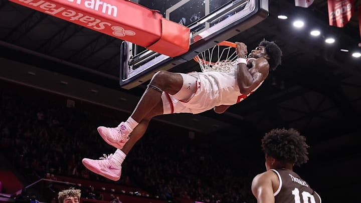 Nov 14, 2025; Piscataway, New Jersey, USA; Rutgers Scarlet Knights center Emmanuel Ogbole (21) hangs on the rim after dunking the ball during the second half against the Lehigh Mountain Hawks at Jersey Mike's Arena. Mandatory Credit: Vincent Carchietta-Imagn Images