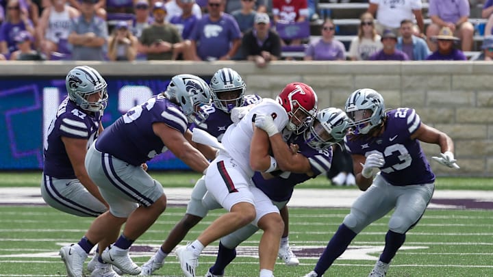 Troy Trojans quarterback Goose Crowder (9) is tackled by Kansas State Wildcats linebacker Austin Romaine (45) and defensive tackle Damian Ilalio (56) during the fourth quarter of a 2023 matchup at Bill Snyder Family Football Stadium.