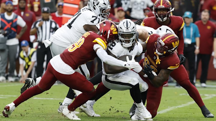 Sep 21, 2025; Landover, Maryland, USA; Las Vegas Raiders running back Ashton Jeanty (2) is tackled by Washington Commanders safety Jeremy Reaves (39) and Commanders defensive end Dorance Armstrong (92) during the third quarter at Northwest Stadium. Mandatory Credit: Geoff Burke-Imagn Images