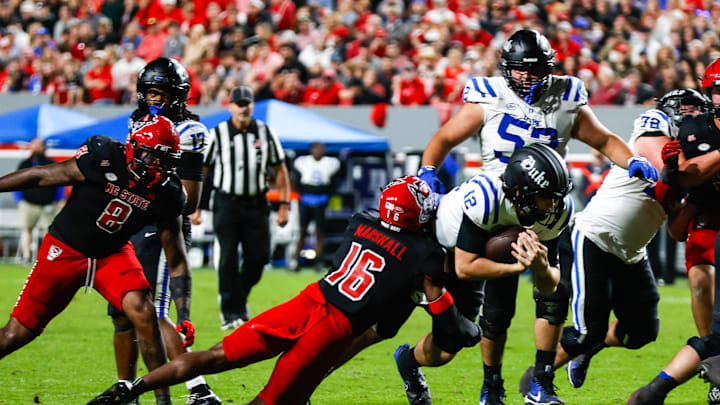 Nov 9, 2024; Raleigh, North Carolina, USA; North Carolina State Wolfpack cornerback Devon Marshall (16) tackles Duke Blue Devils quarterback Grayson Loftis (12) during the second half of the game at Carter-Finley Stadium. Mandatory Credit: Jaylynn Nash-Imagn Images