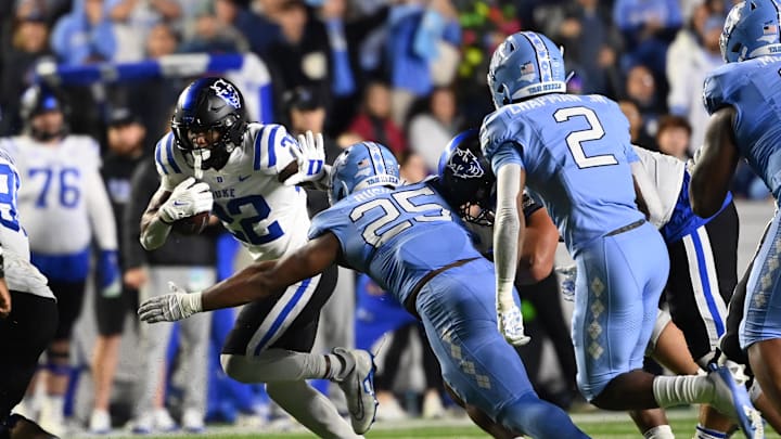 Nov 11, 2023; Chapel Hill, North Carolina, USA; Duke Blue Devils running back Jaylen Coleman (22) runs as North Carolina Tar Heels linebacker Kaimon Rucker (25) and defensive back Don Chapman (2) defend in the fourth quarter at Kenan Memorial Stadium. Mandatory Credit: Bob Donnan-USA TODAY Sports