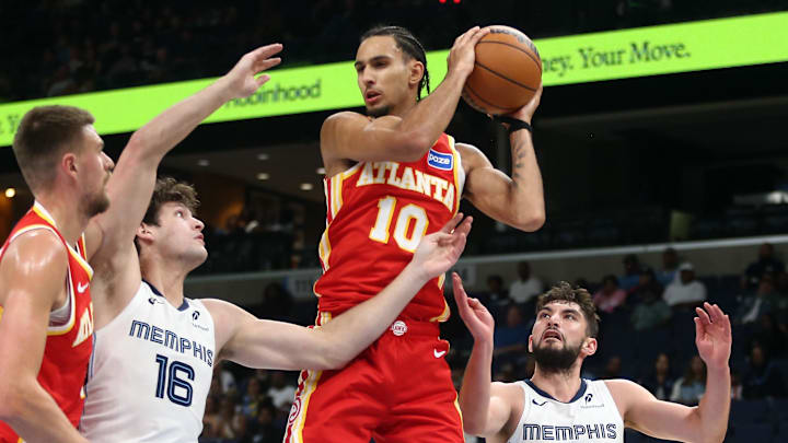 Oct 11, 2025; Memphis, Tennessee, USA; Atlanta Hawks forward Zaccharie Risacher (10) collects a rebound over Memphis Grizzlies center PJ Hall (16) and guard Ty Jerome (2) during the third quarter at FedExForum. Mandatory Credit: Petre Thomas-Imagn Images