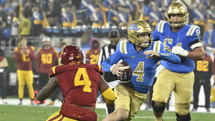 Nov 23, 2024; Pasadena, California, USA; UCLA Bruins quarterback Ethan Garbers (4) runs past USC Trojans linebacker Easton Mascarenas-Arnold (4) during the third quarter at Rose Bowl. Mandatory Credit: Robert Hanashiro-Imagn Images