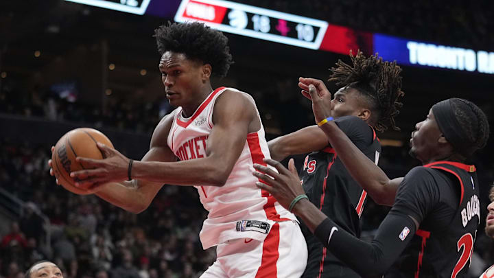 Dec 22, 2024; Toronto, Ontario, CAN; Houston Rockets forward Amen Thompson (1) comes down with a rebound against Toronto Raptors guard Ja'Kobe Walter (14) and  forward Chris Boucher (25) during the second half at Scotiabank Arena. Mandatory Credit: John E. Sokolowski-Imagn Images