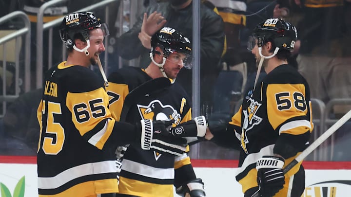 Mar 30, 2025; Pittsburgh, Pennsylvania, USA;  Pittsburgh Penguins defenseman Erik Karlsson (65) and center Sidney Crosby (middle) and defenseman Kris Letang (58) celebrate after defeating the Ottawa Senators in overtime at PPG Paints Arena. Mandatory Credit: Charles LeClaire-Imagn Images