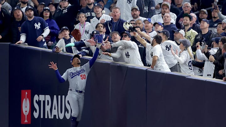 Oct 29, 2024; New York, New York, USA; Los Angeles Dodgers shortstop Mookie Betts (50) makes a catch in foul territory as a New York Yankees fan interferes during the first inning in game four of the 2024 MLB World Series at Yankee Stadium. Mandatory Credit: Brad Penner-Imagn Images