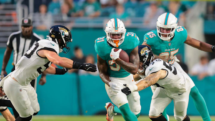 Aug 23, 2025; Miami Gardens, Florida, USA; Miami Dolphins running back Ollie Gordon II (31) runs with the football past Jacksonville Jaguars linebacker Dennis Gardeck (57) and linebacker Branson Combs (50) during the second quarter at Hard Rock Stadium. Mandatory Credit: Sam Navarro-Imagn Images