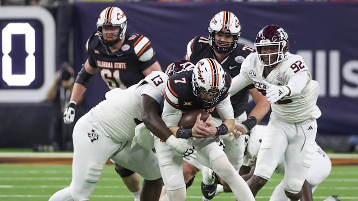 Dec 27, 2023; Houston, TX, USA; Oklahoma State Cowboys quarterback Alan Bowman (7) is tackled b y Texas A&M Aggies defensive lineman DJ Hicks (13) in the second quarter at NRG Stadium. Mandatory Credit: Thomas Shea-Imagn Images