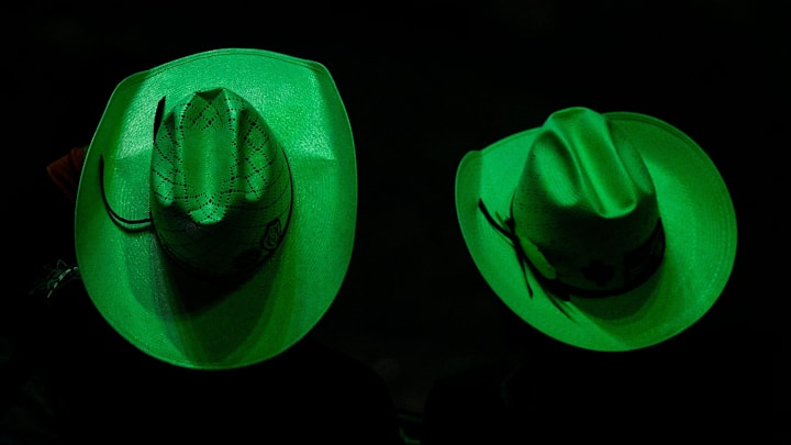 A green light illuminates audience members hats as they watch the second day PBR Gambler Days at the Moody Center in Austin, Saturday Aug. 24, 2024. Gambler Days is part of Professional Bull Riding's World Team Series, where teams of riders compete against other teams by adding their scores together, if they manage to stay on the bull for more than eight seconds.