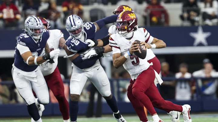 Jan 5, 2025; Arlington, Texas, USA;  Washington Commanders quarterback Jayden Daniels (5) runs with the ball past Dallas Cowboys defensive end Chauncey Golston (99) during the first half at AT&T Stadium. Mandatory Credit: Kevin Jairaj-Imagn Images