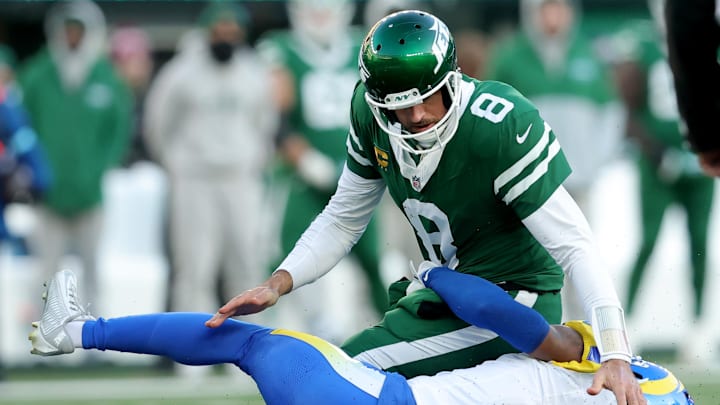 Dec 22, 2024; East Rutherford, New Jersey, USA; New York Jets quarterback Aaron Rodgers (8) fumbles the ball after a hit by Los Angeles Rams safety Kamren Curl (3) during the fourth quarter at MetLife Stadium. 