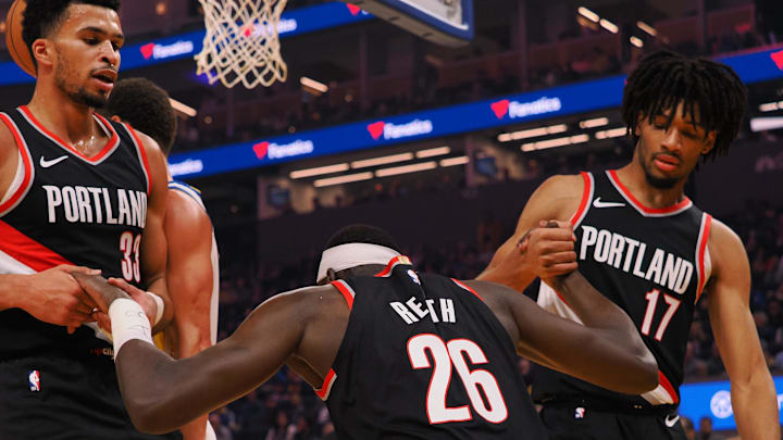 Dec 6, 2023; San Francisco, California, USA;  Portland Trailblazers center Duop Reath (26) is helped up by forward Toumani Camara (33) and guard Shaedon Sharpe (17) after being fouled by the Golden State Warriors during the first quarter at Chase Center. Mandatory Credit: Kelley L Cox-Imagn Images