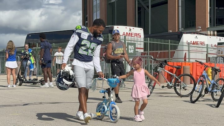Julian Love takes a young girl's bike to the Packers-Seahawks joint practice on Thursday.