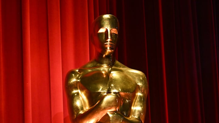 A golden Oscars statue stands against a red curtain