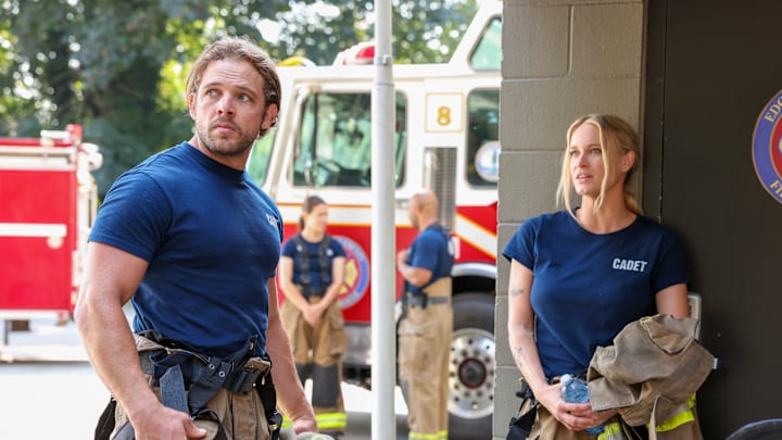 L-R: Bode Leone looking over his shoulder. Audrey James is leaning against the wall behind him. Fire Country. L-R: Bode Leone looking over his shoulder. Audrey James is leaning against the wall behind him. Fire Country.