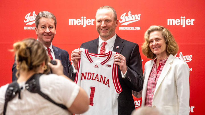 Indiana University Vice President and Director of Intercollegiate Athletics Scott Dolson, Indiana University men's basketball Head Coach Darian DeVries and Indiana University President Pamela Whitten pose with a jersey at the introductory press conference at Simon Skjodt Assembly Hall on Wednesday, March 19, 2025.