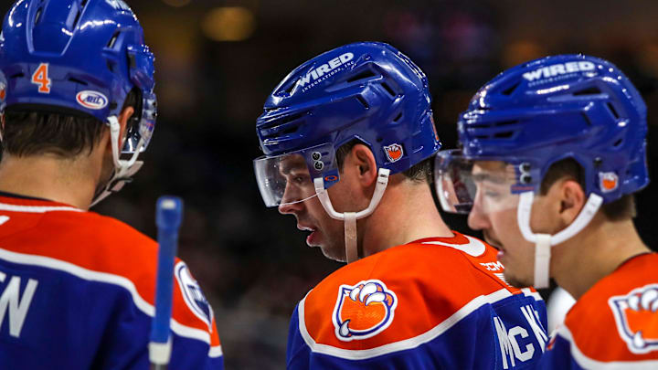 Bakersfield forward Greg McKegg (14) talks with defenseman Cam Dineen (4) and other teammates during