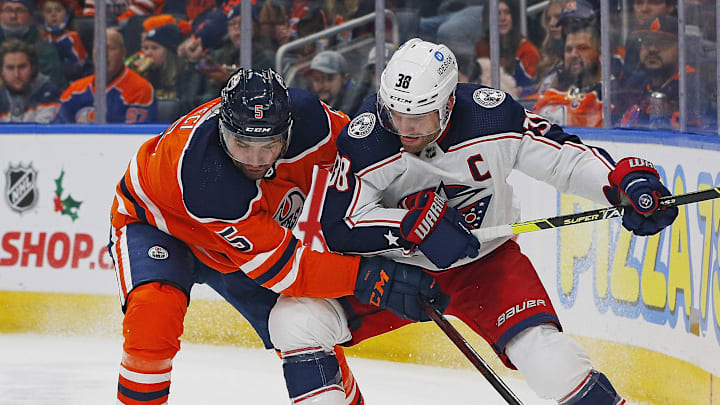 Dec 16, 2021; Edmonton, Alberta, CAN; Columbus Blue Jackets forward Boone Jenner (38) and Edmonton Oilers defensemen Cody Ceci (5) battle for a loose puck during the second period at Rogers Place. Mandatory Credit: Perry Nelson-Imagn Images