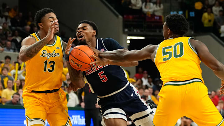 Feb 17, 2025; Waco, Texas, USA;  Arizona Wildcats guard KJ Lewis (5) drives to the basket between Baylor Bears guard Langston Love (13) and guard Jalen Celestine (50) during the first half at Paul and Alejandra Foster Pavilion. Mandatory Credit: Chris Jones-Imagn Images