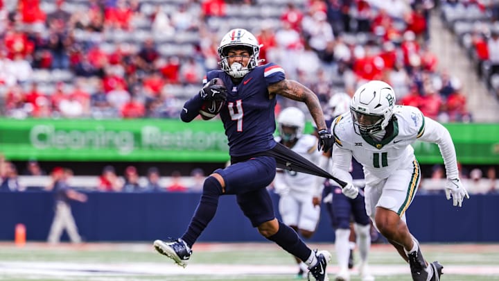 Nov 22, 2025; Tucson, Arizona, USA; Arizona Wildcats wide receiver Kris Hutson (4) catches the ball while Baylor Bears linebacker Keaton Thomas (11) pulls on his jersey during the third quarter of the game at Casino Del Sol Stadium. Mandatory Credit: Aryanna Frank-Imagn Images