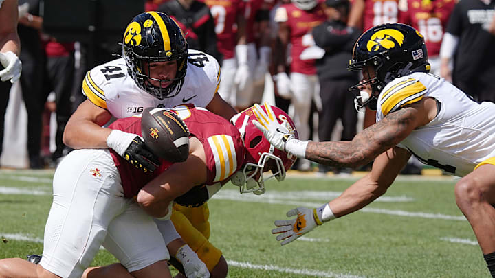 Iowa State Cyclones' running back Carson Hansen (26) looses the ball as getting tackler by Iowa Hawkeyes linebacker Jaden Harrell (41) and defensive back TJ Hall (2) during the first quarter in the Cy-Hawk Series at Jack Trice Stadium on Sept. 6, 2025, in Ames, Iowa