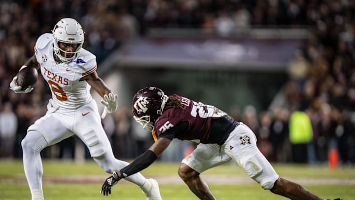 Nov 30, 2024; College Station, Texas, USA; Texas Longhorns tight end Amari Niblack (8) runs with the ball, bracing for a tackle from Texas A&M Aggies defensive back Will Lee III (26) in the second quarter of the Lone Star Showdown game at Kyle Field. Mandatory Credit: Sara Diggins/USA TODAY Network via Imagn Images