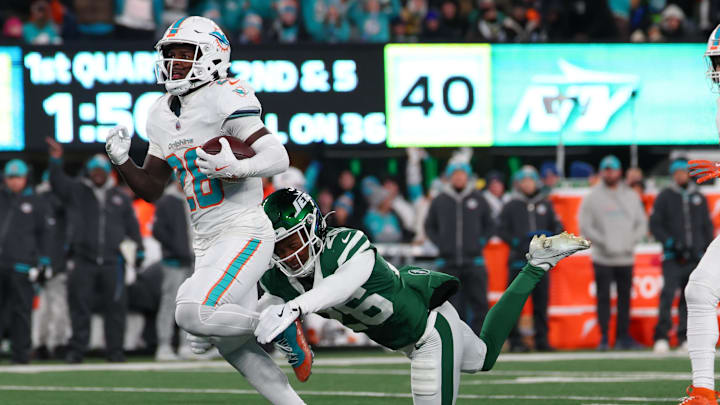 Miami Dolphins running back De'Von Achane (28) runs with the ball while avoiding a tackle attempt by New York Jets cornerback Brandin Echols (26) during the first quarter at MetLife Stadium. 