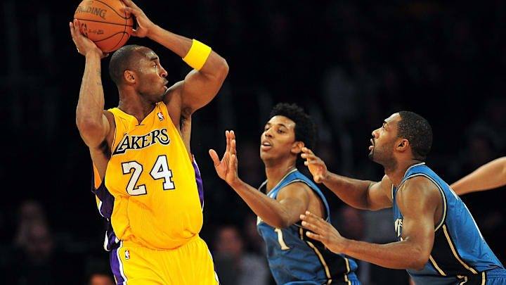 December 7, 2010; Los Angeles, CA, USA; Los Angeles Lakers shooting guard Kobe Bryant (24) passes the ball against the defense of Washington Wizards shooting guard Nick Young (1) and point guard Gilbert Arenas (9) during the firsthalf at the Staples Center. Mandatory Credit: Gary A. Vasquez-Imagn Images