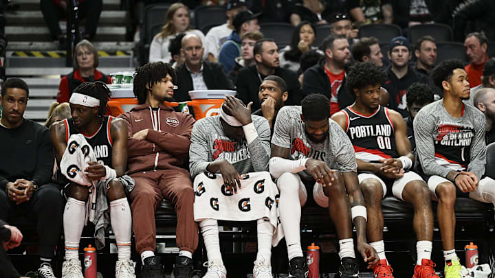 Mar 11, 2024; Portland, Oregon, USA; The Portland Trail Blazers bench, from left, guard Malcolm Brogdon (11), guard Shaedon Sharpe (17), center Duop Reath (26), center Deandre Ayton (2), guard Scoot Henderson (00), and guard Anfernee Simons (1) watch the final minutes of a game against the Boston Celtics at Moda Center. Mandatory Credit: Troy Wayrynen-Imagn Images