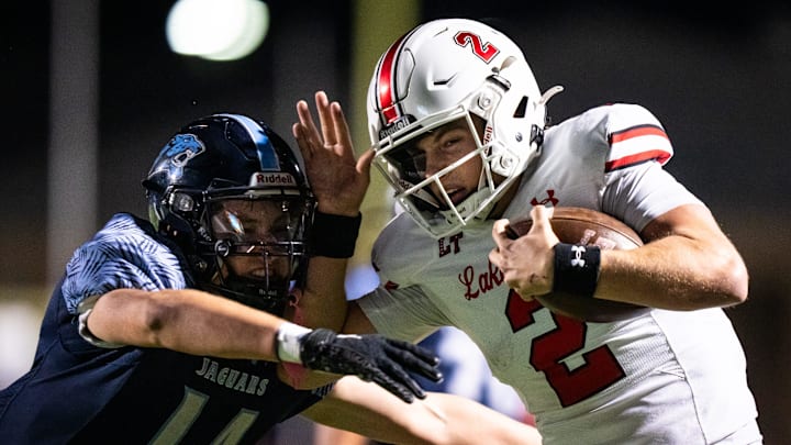 Lake Travis quarterback Chasten Ditto (2) carries the ball while fending off defense from San Antonio Jonhson defensive back Jacob Mazzacco (14) in the third quarter of the Cavaliers' area round 6A Division I UIL State Championship playoff game against the San Antonio Johnson Jaguars at Rattler Stadium in San Marcos, Nov. 22, 2024.