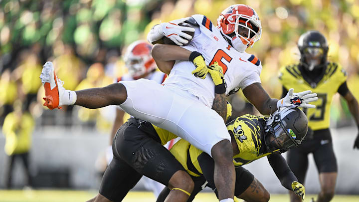 Oct 26, 2024; Eugene, Oregon, USA; Illinois Fighting Illini running back Josh McCray (6) is upended by Oregon Ducks linebacker Jestin Jacobs (4) and defensive back Daylen Austin (27) during the second half at Autzen Stadium. Mandatory Credit: Troy Wayrynen-Imagn Images Oct 26, 2024; Eugene, Oregon, USA; Illinois Fighting Illini running back Josh McCray (6) is upended by Oregon Ducks linebacker Jestin Jacobs (4) and defensive back Daylen Austin (27) during the second half at Autzen Stadium. Mandatory Credit: Troy Wayrynen-Imagn Images