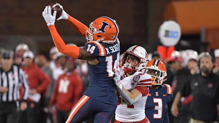 Oct 6, 2023; Champaign, Illinois, USA; Illinois Fighting Illini defensive back Xavier Scott (14) intercepts the ball in front of intended Nebraska Cornhuskers wide receiver Alex Bullock (84) during the second half at Memorial Stadium. Mandatory Credit: Ron Johnson-Imagn Images