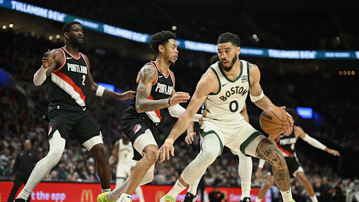 Mar 11, 2024; Portland, Oregon, USA; Boston Celtics forward Jayson Tatum (0) drives to the basket during the second half against Portland Trail Blazers guard Anfernee Simons (1) and center Deandre Ayton (2) at Moda Center. Mandatory Credit: Troy Wayrynen-Imagn Images