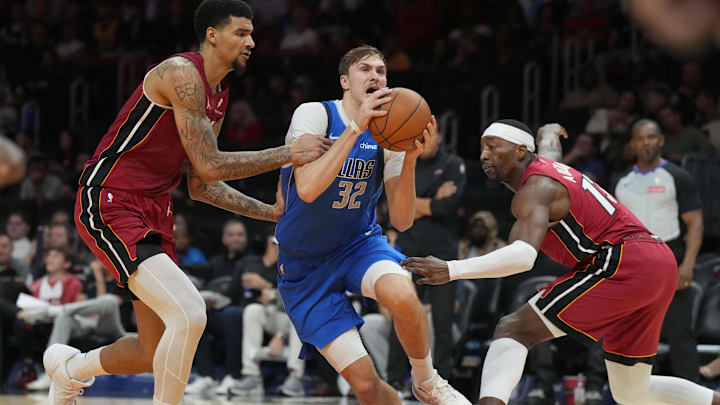 Nov 24, 2025; Miami, Florida, USA; Dallas Mavericks forward Cooper Flagg (32) splits the defense of Miami Heat forward Bam Adebayo (13) and center Kel'el Ware (7) during the second half at Kaseya Center. Mandatory Credit: Jim Rassol-Imagn Images