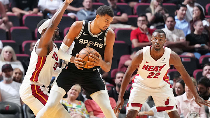 Oct 8, 2025; Miami, Florida, USA; San Antonio Spurs center Victor Wembanyama (1) looks for room as Miami Heat center Bam Adebayo (13) and forward Andrew Wiggins (22) defend during the first half at Kaseya Center. Mandatory Credit: Jim Rassol-Imagn Images Oct 8, 2025; Miami, Florida, USA; San Antonio Spurs center Victor Wembanyama (1) looks for room as Miami Heat center Bam Adebayo (13) and forward Andrew Wiggins (22) defend during the first half at Kaseya Center. Mandatory Credit: Jim Rassol-Imagn Images