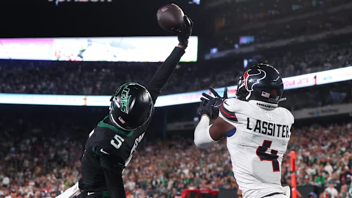 Oct 31, 2024; East Rutherford, New Jersey, USA; New York Jets wide receiver Garrett Wilson (5) catches a touchdown pass while being defended by Houston Texans cornerback Kamari Lassiter (4) during the second half at MetLife Stadium.