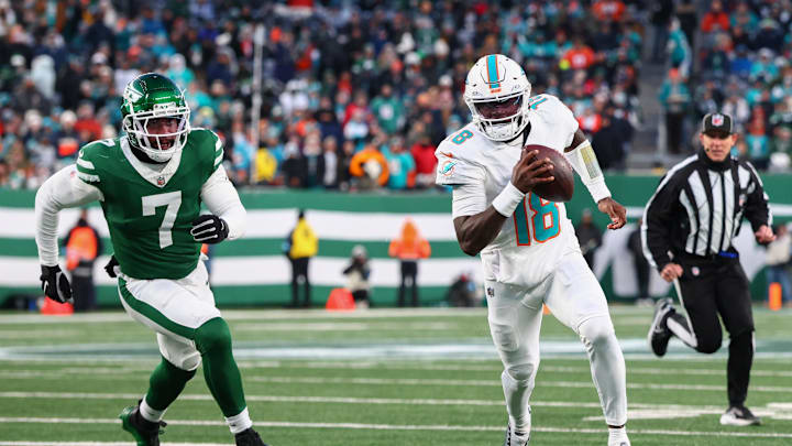 Jan 5, 2025; East Rutherford, New Jersey, USA; Miami Dolphins quarterback Tyler Huntley (18) runs with the ball while being pursued by New York Jets defensive end Haason Reddick (7) during the second quarter at MetLife Stadium. Mandatory Credit: Ed Mulholland-Imagn Images