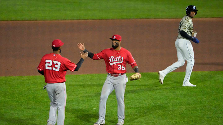 Louisville Bats third baseman Cristian Santana (23) high fives first baseman Allen C  rdoba (39) as Columbus Clippers right fielder Oscar Gonzalez (39) leaves the field following the Minor League Baseball game at Huntington Park in Columbus on April 27, 2022. The Bats won 7-5.