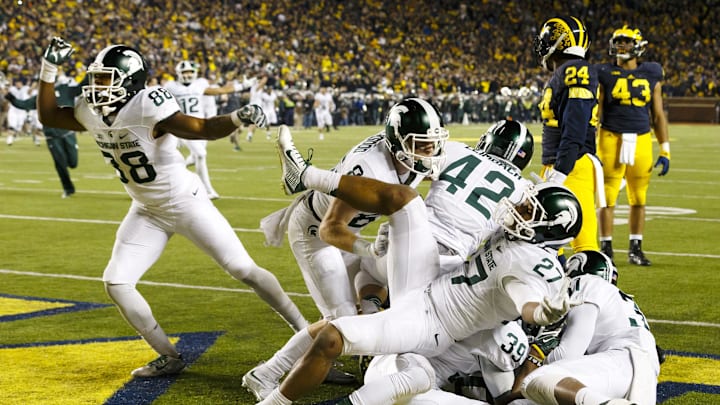 Oct 17, 2015; Ann Arbor, MI, USA; Michigan State Spartans defensive back Jalen Watts-Jackson (20) is mobbed by teammates after scoring a touchdown as the clock expires in the fourth quarter against the Michigan Wolverines at Michigan Stadium. Michigan State 27-23. Mandatory Credit: Rick Osentoski-Imagn Images