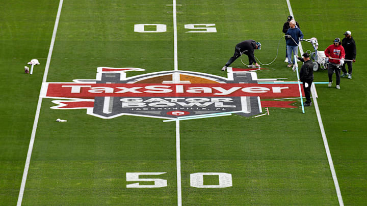 The turf crew at EverBank Stadium put the final touches on the TaxSlayer Gator Bowl logo at midfield Thursday, December 28, 2023, the day before the University of Kentucky takes on the Clemson Tigers in the 2023 Gator Bowl game in Jacksonville, Florida. [Bob Self/Florida Times-Union]