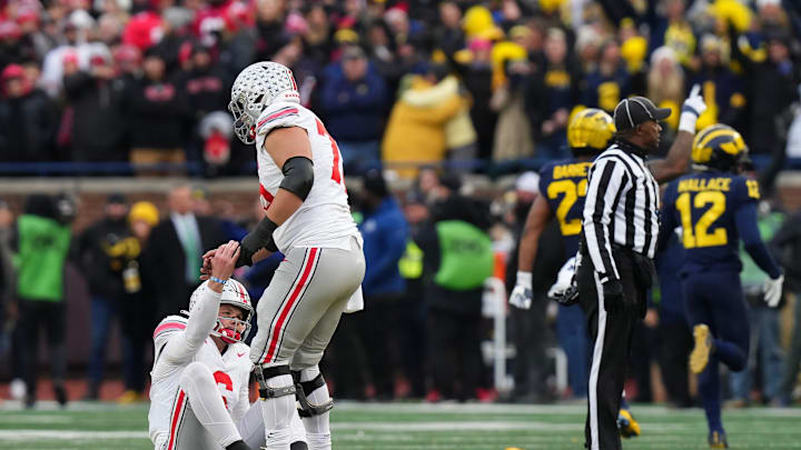 Ohio State Buckeyes offensive lineman Carson Hinzman (75) helps up quarterback Kyle McCord (6) 