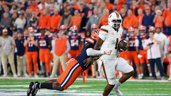 Nov 30, 2024; Syracuse, New York, USA; Miami Hurricanes quarterback Cam Ward (1) runs with the ball as Syracuse Orange linebacker Marlowe Wax (left) attempts to make a tackle during the second half at the JMA Wireless Dome. Mandatory Credit: Rich Barnes-Imagn Images