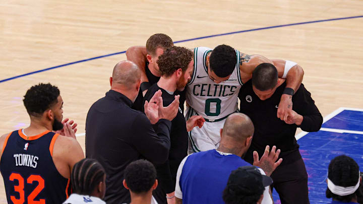 May 12, 2025; New York, New York, USA; Boston Celtics forward Jayson Tatum (0) is helped off the court by after an injury in the second half during game four of the second round for the 2025 NBA Playoffs against the New York Knicks at Madison Square Garden. Tatum would leave the game with an injury after this play. Mandatory Credit: Vincent Carchietta-Imagn Images