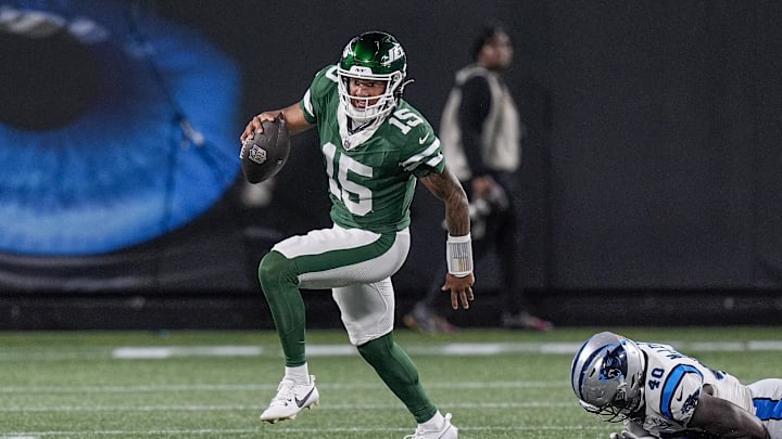 Aug 17, 2024; Charlotte, North Carolina, USA;  New York Jets quarterback Adrian Martinez (15) gets away from a tackle by Carolina Panthers defensive end Derrick McLendon (40) during the second half at Bank of America Stadium