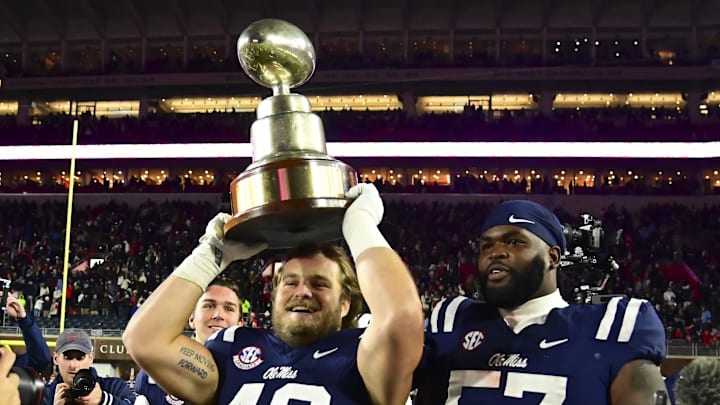 Nov 29, 2024; Oxford, Mississippi, USA; Mississippi Rebels players react with the Egg Bowl trophy after the game against the Mississippi State Bulldogs at Vaught-Hemingway Stadium. Mandatory Credit: Matt Bush-Imagn Images