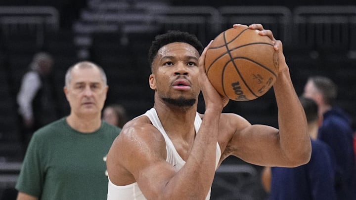 Mar 29, 2026; Milwaukee, Wisconsin, USA; Milwaukee Bucks forward Giannis Antetokounmpo (34) shoots during pregame warmups  as his personal trainer Michael Kalavros looks on from the back left before a game against the LA Clippers at Fiserv Forum. Mandatory Credit: Michael McLoone-Imagn Images